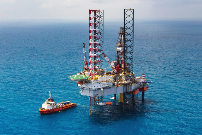 Oil rig in ocean with ship nearby