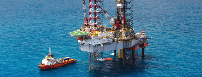 Oil rig in ocean with ship nearby