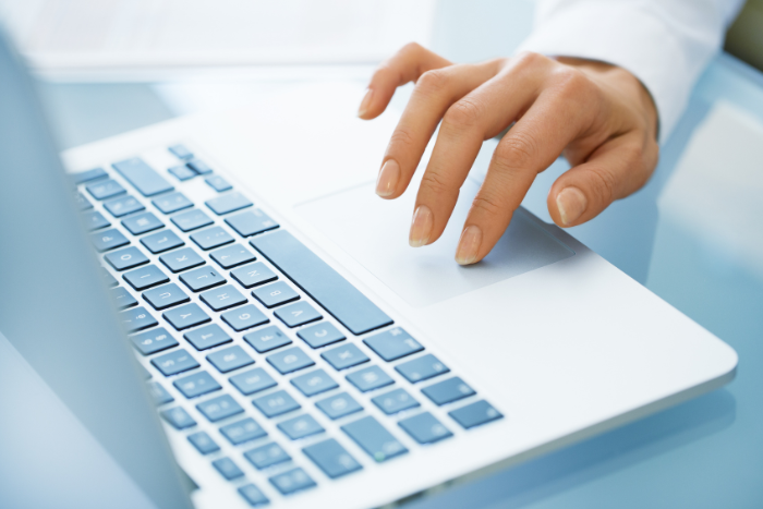 Hand typing on laptop keyboard