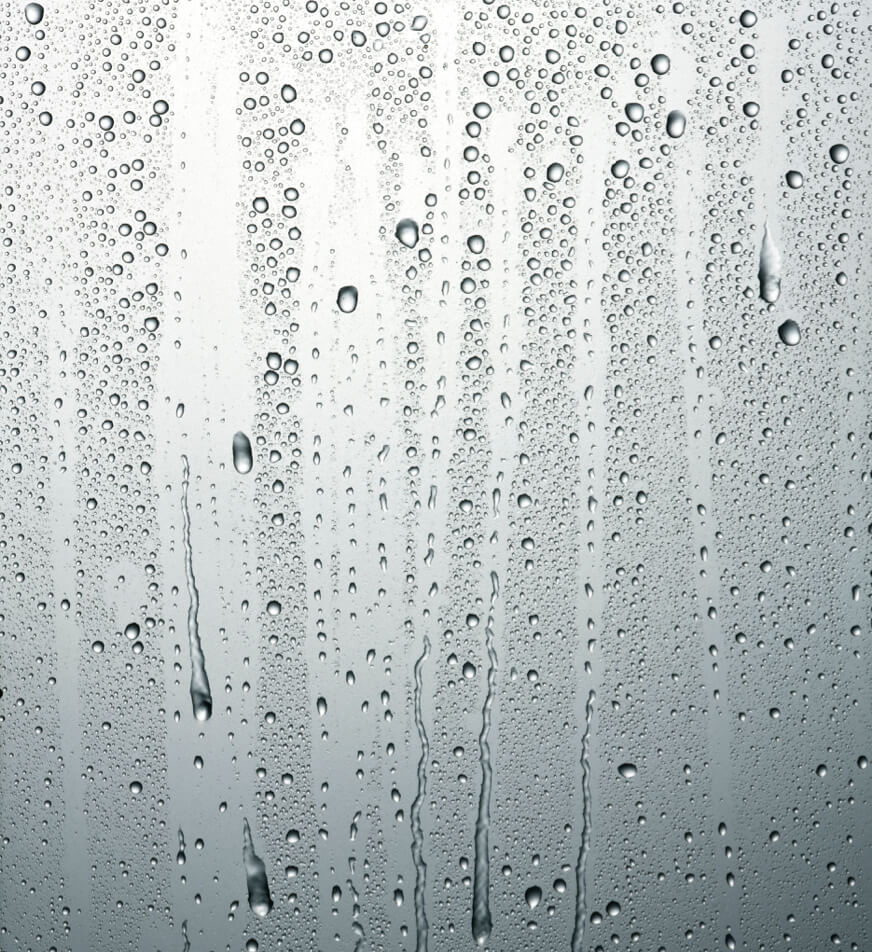 Raindrops dripping down a smooth surface.